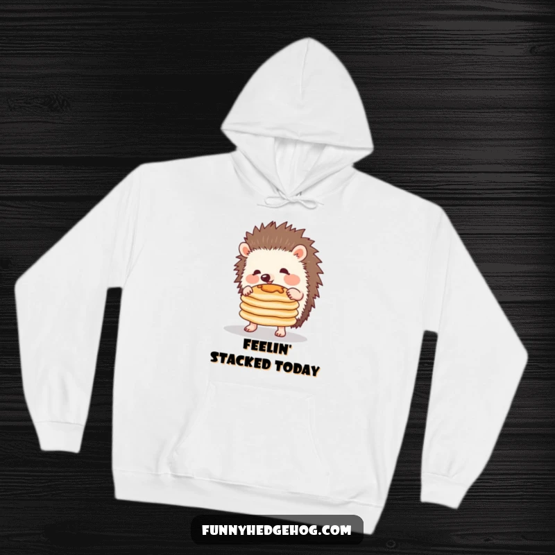 Funny hoodie showcasing a delightful hedgehog attempting to balance a stack of pancakes, radiating pure, comical joy and effort.